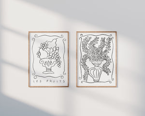 two prints of charcoal drawings in black and white featuring fruits and botanicals in vases